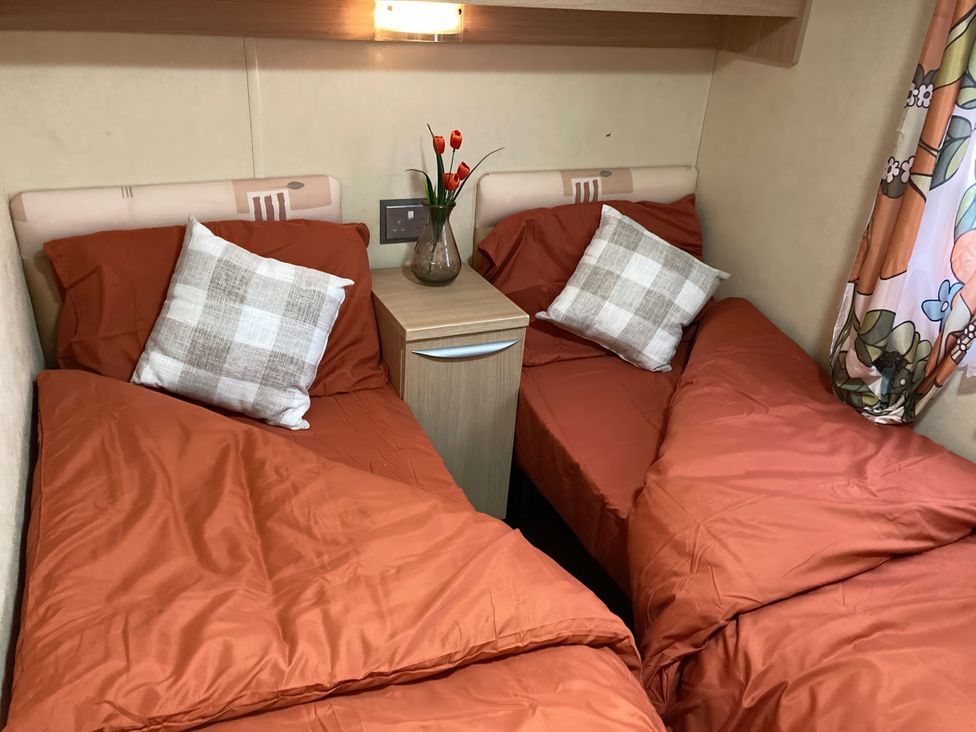 A bedroom with two beds and a nightstand at Beachside in Towyn