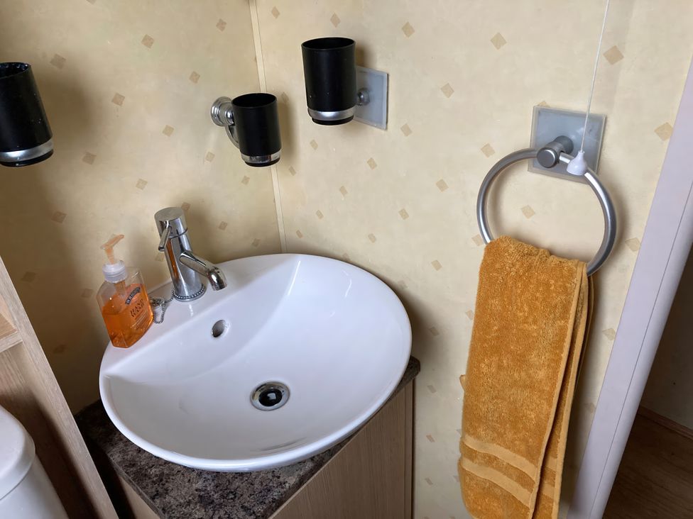A bathroom with a sink and orange towel at Beachside in Towyn