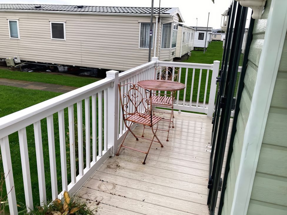 A deck with a table and chairs at Beachside in Towyn
