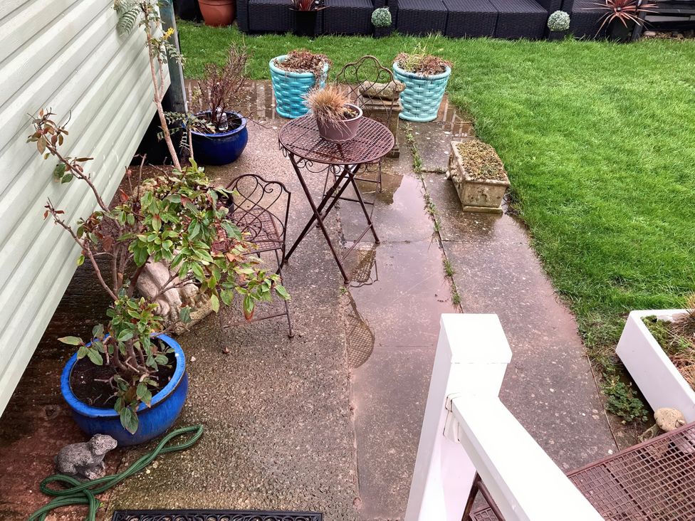 An outdoor area with a table and chairs and potted plants at Beachside in Towyn