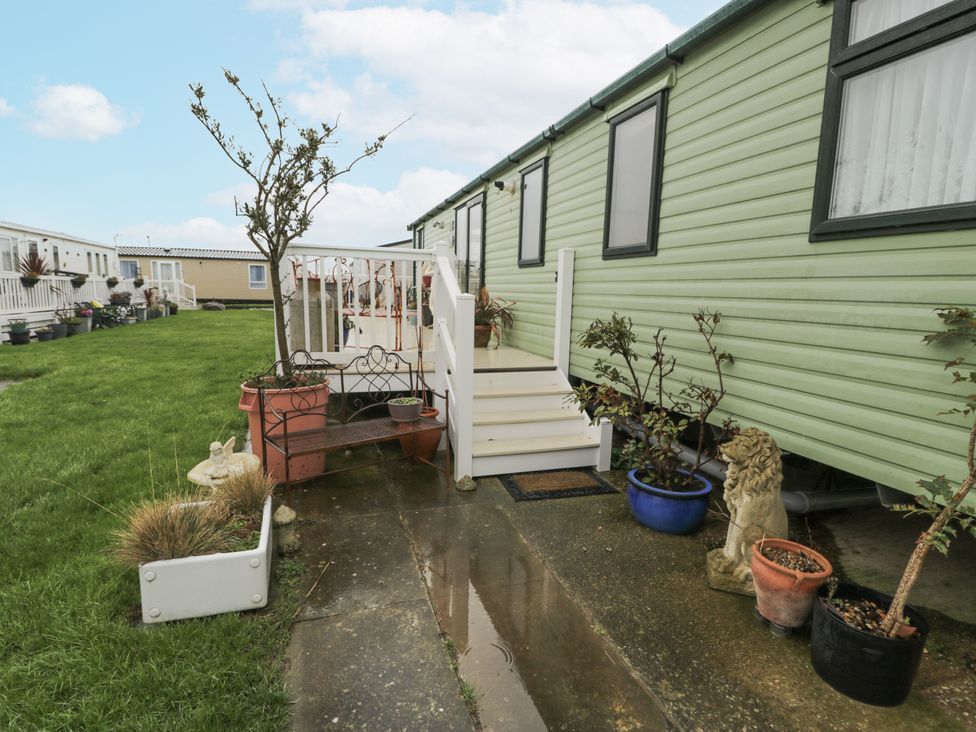 An outdoor view of a mobile home with steps and garden features at Beachside in Towyn
