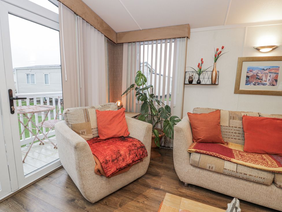 A living room with armchairs and a plant at Beachside in Towyn