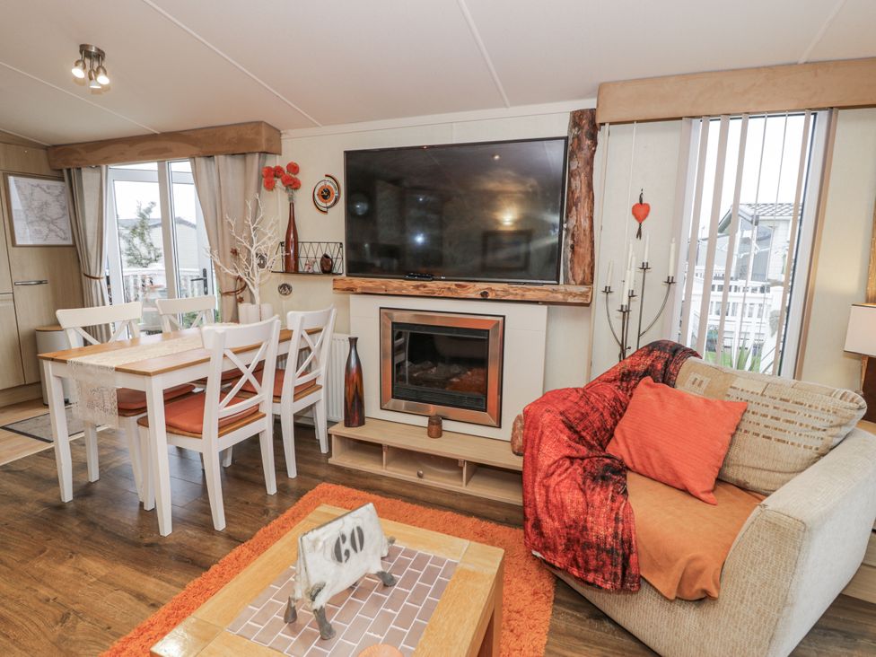 A living room with a television and dining area at Beachside in Towyn