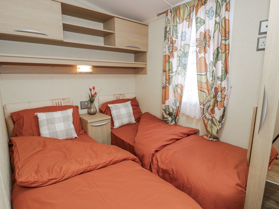 A bedroom with two beds and a bedside table at Beachside in Towyn