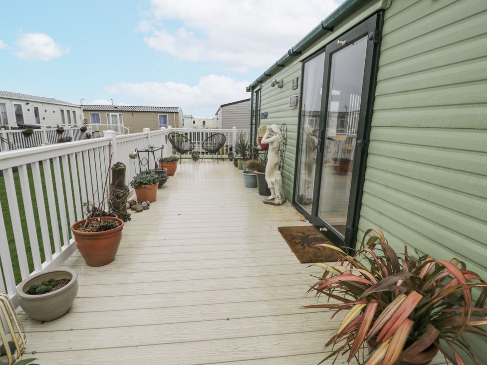An outdoor deck with potted plants and chairs at Beachside in Towyn