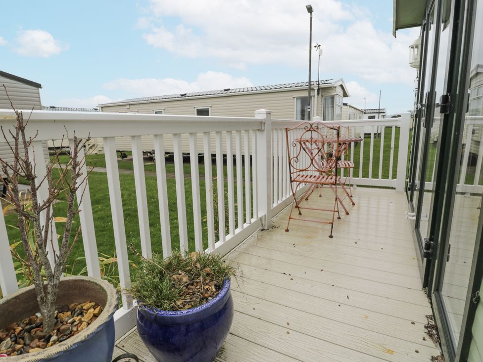 A balcony with chairs and plant pots at Beachside in Towyn