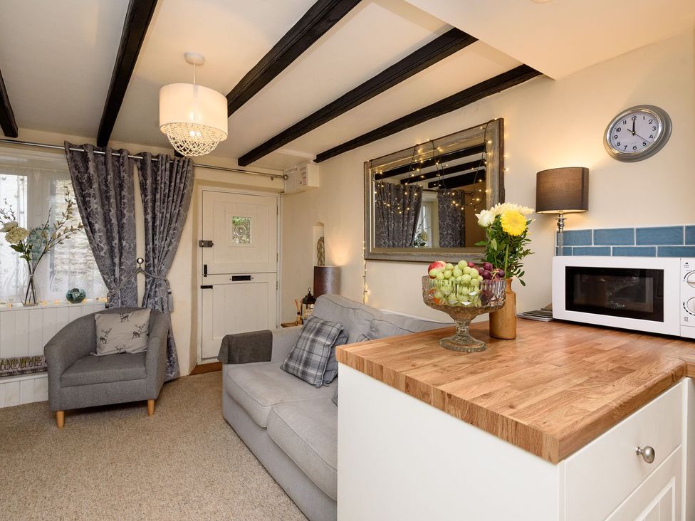 A living room with a sofa and armchair at Dolls Cottage in Looe