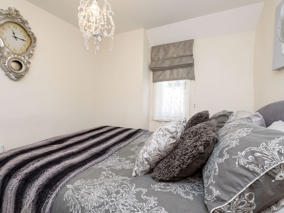 A bedroom with a bed and a clock at Dolls Cottage in Looe