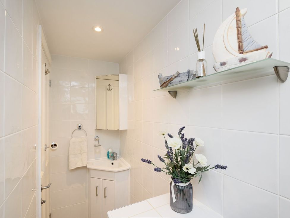 A bathroom with a sink and decor at Dolls Cottage in Looe