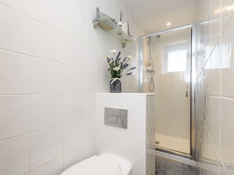 A bathroom featuring a shower and toilet at Dolls Cottage in Looe