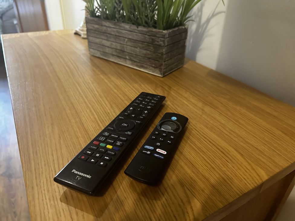 A wooden table with remote controls and a decorative plant at The Rocks in Newry