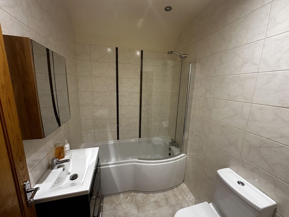 A bathroom with a bathtub, toilet, sink, and mirror at The Rocks in Newry