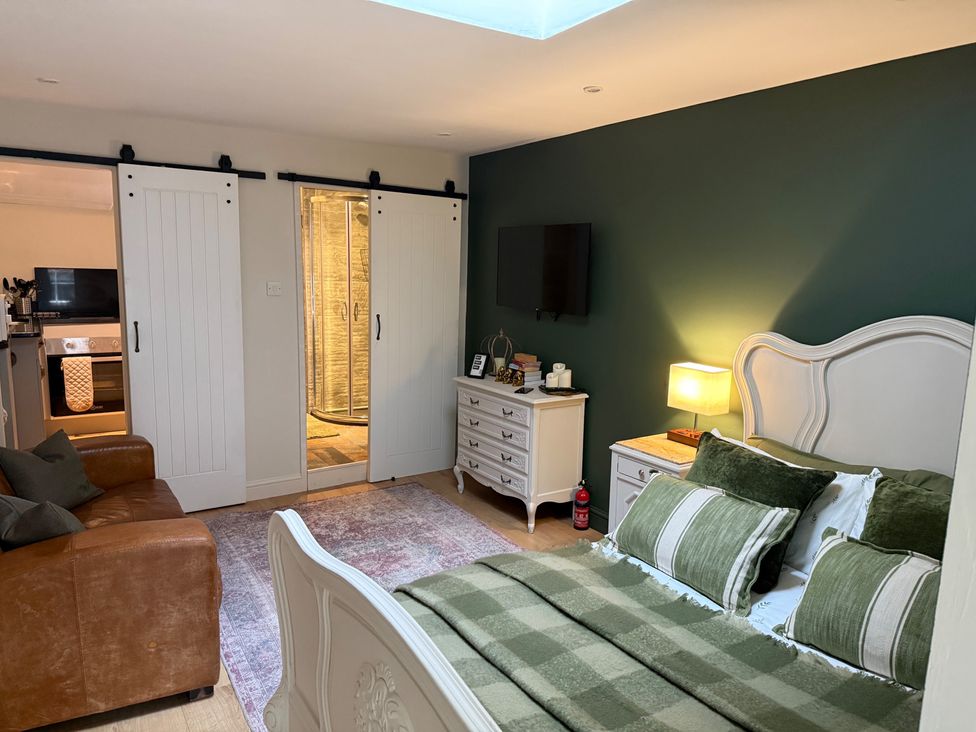 A bedroom with a bed, sofa, television, and dresser at Studio Apartment at High Dyke Farm Cockermouth