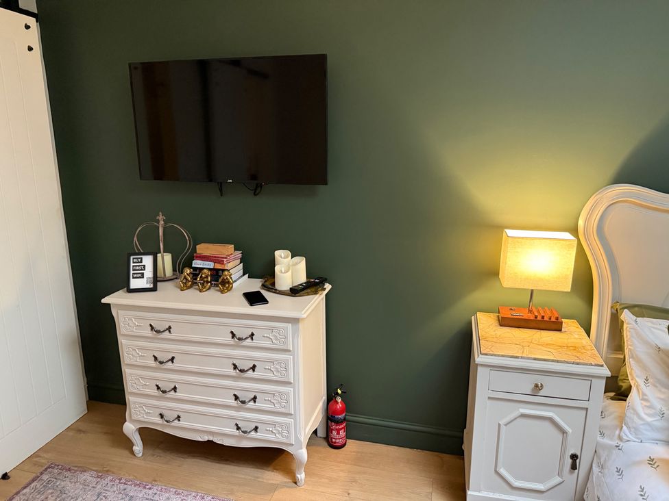 A bedroom with a television on the wall and chest of drawers at Studio Apartment at High Dyke Farm Cockermouth