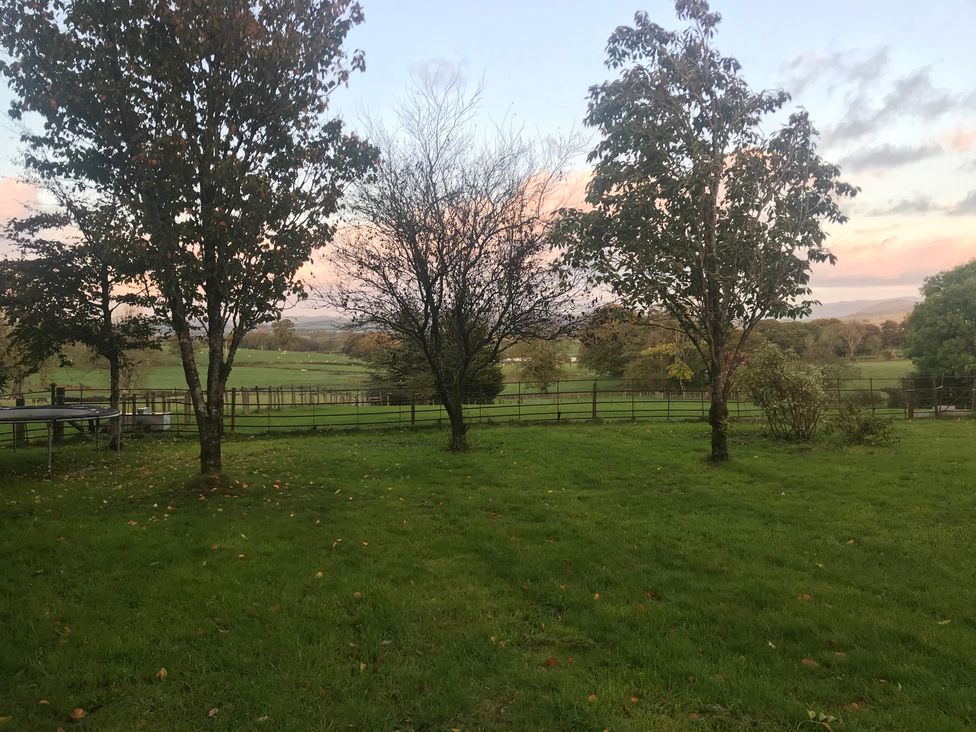 A grassy area with trees and a fence at Studio Apartment at High Dyke Farm Cockermouth