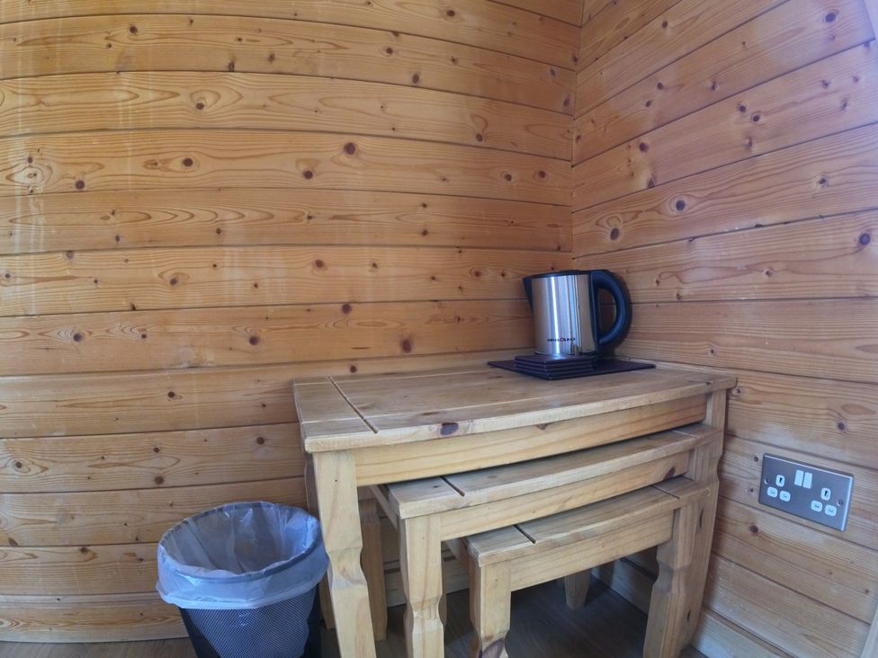 A snug with a wooden table and kettle at Rosebud Meadow Pod 2 Malvern