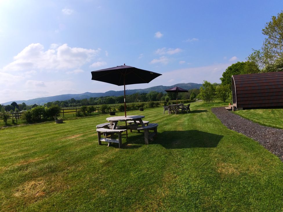 An outdoor area with picnic tables and an umbrella at Rosebud Meadow Pod 4 in Malvern