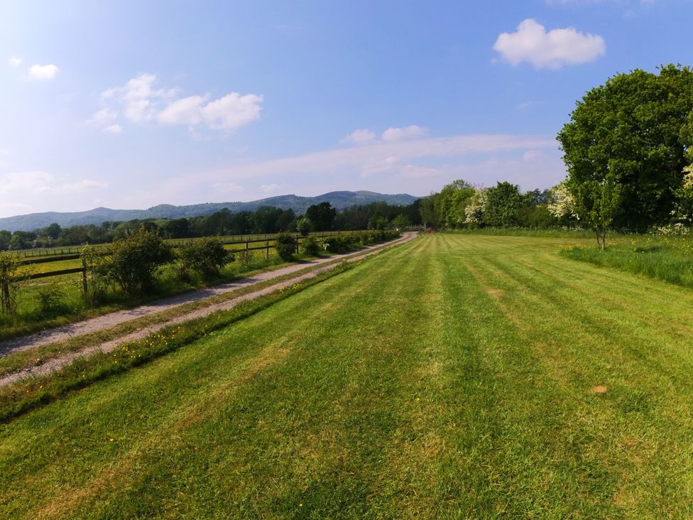 A field with a dirt path and trees at Rosebud Meadow Pod 4 Malvern