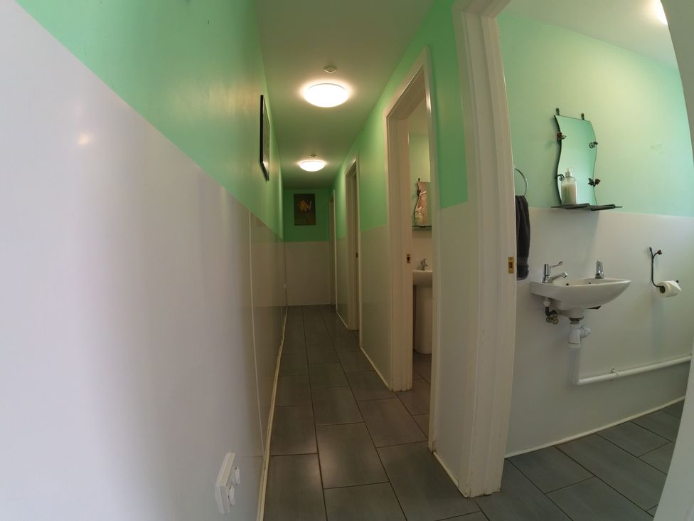 A bathroom hallway with a sink and mirror at Rosebud Meadow Pod 4 in Malvern