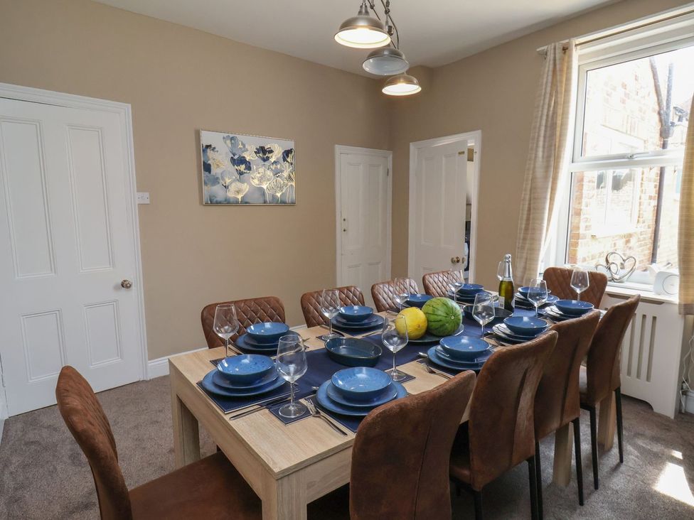 A dining room with a table set for dinner at Crescent Bay House in Filey