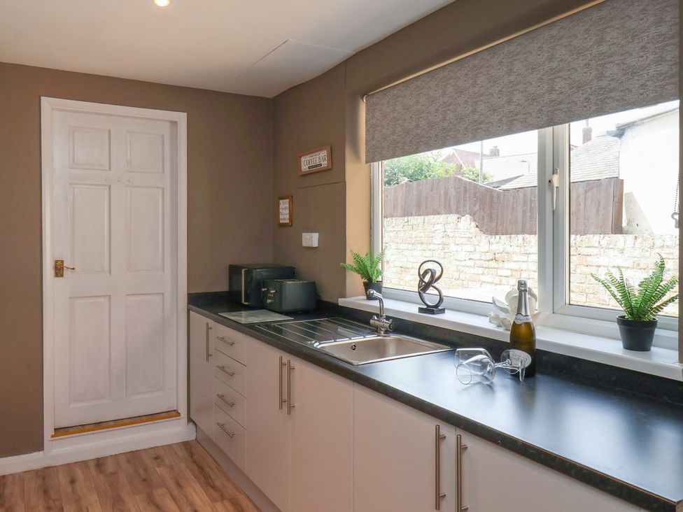 A kitchen with a sink and door at Crescent Bay House in Filey
