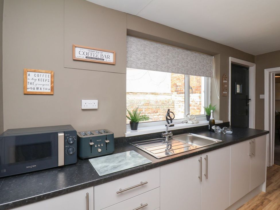 A kitchen with a microwave and toaster near the sink at Crescent Bay House in Filey