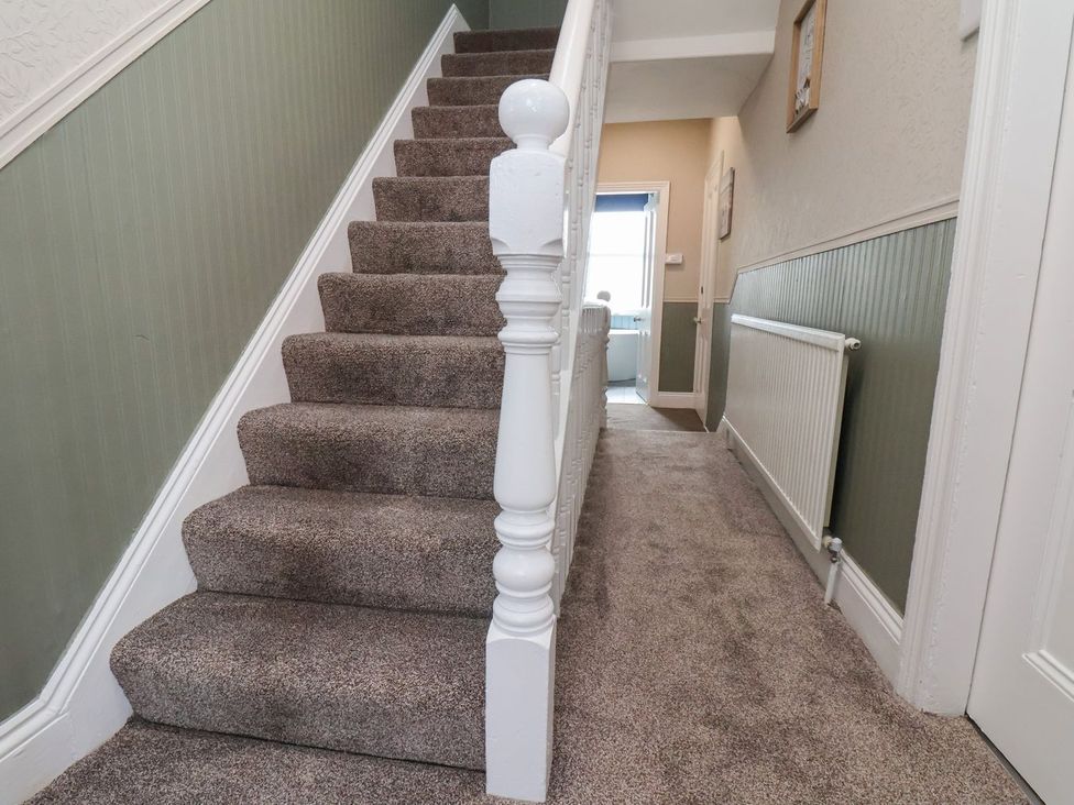 A staircase with a handrail and a hallway at Crescent Bay House in Filey