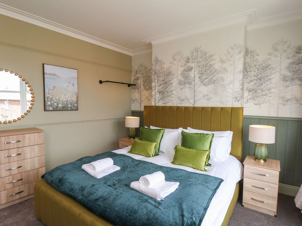 A bedroom with a bed and side table at Crescent Bay House in Filey