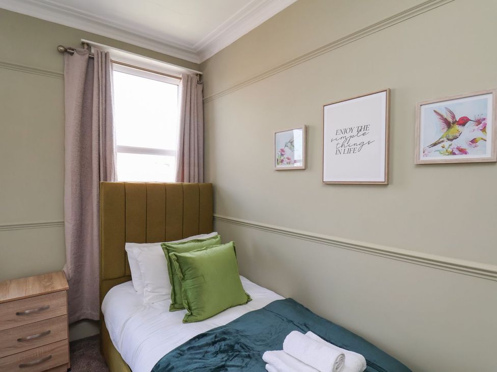 A bedroom with a single bed and pictures on the wall at Crescent Bay House in Filey