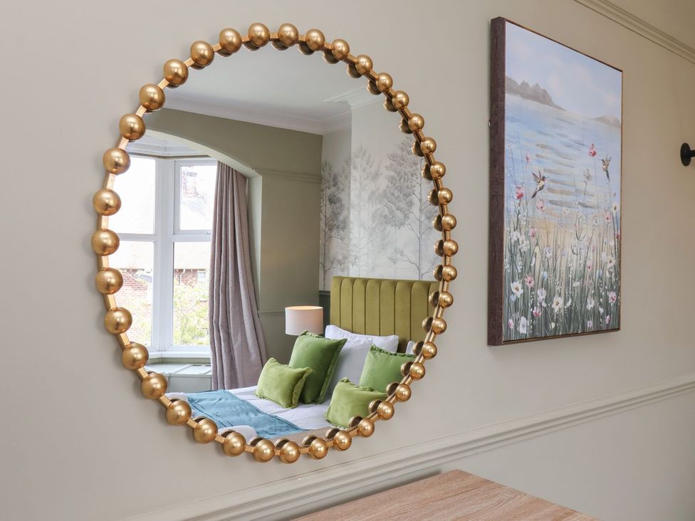A mirror reflecting a bedroom with a bed and decorations at Crescent Bay House in Filey