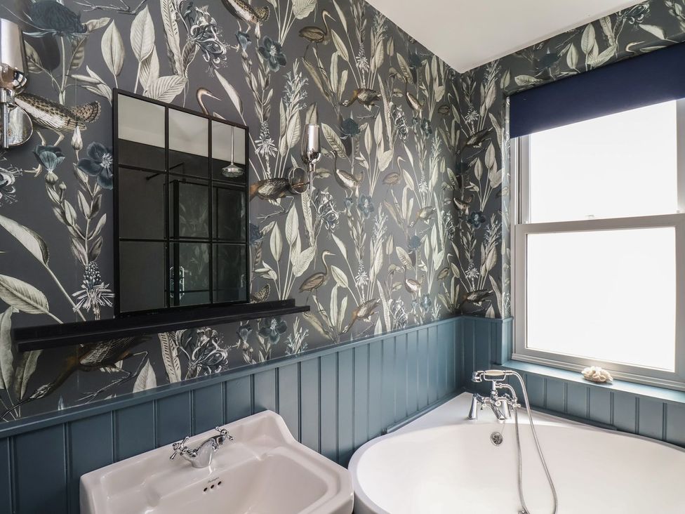 A bathroom with a bathtub and mirror at Crescent Bay House in Filey
