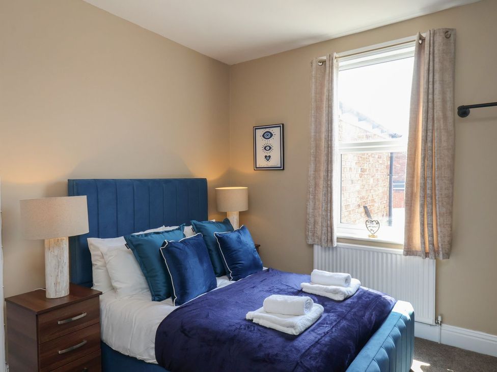 A bedroom with a bed and bedside table at Crescent Bay House in Filey