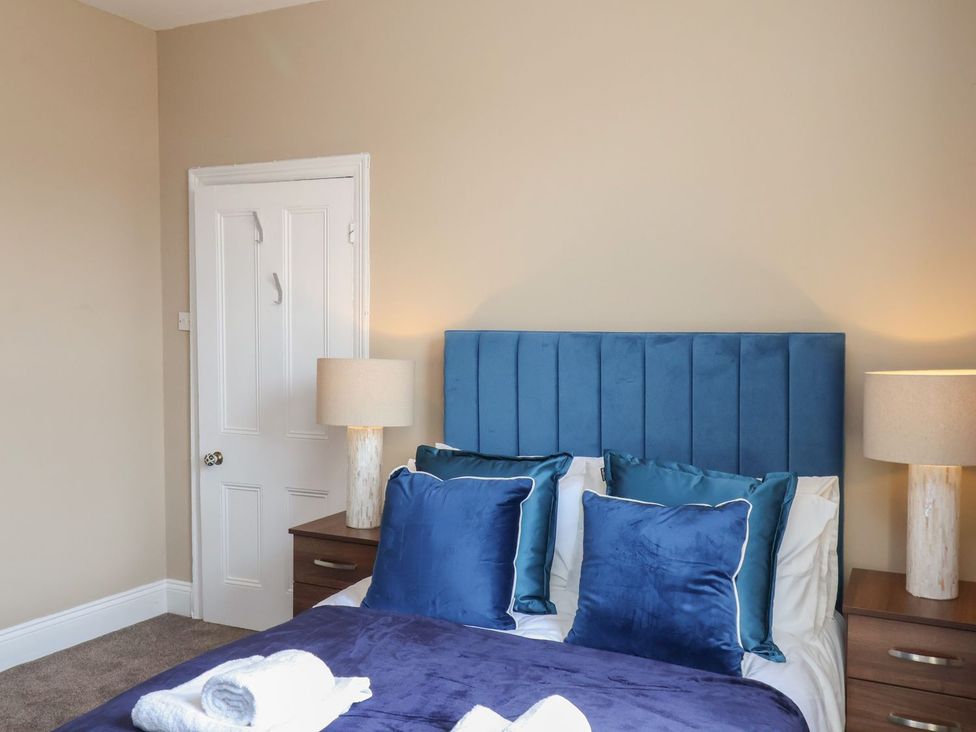 A bedroom with a blue bed and bedside lamps at Crescent Bay House in Filey