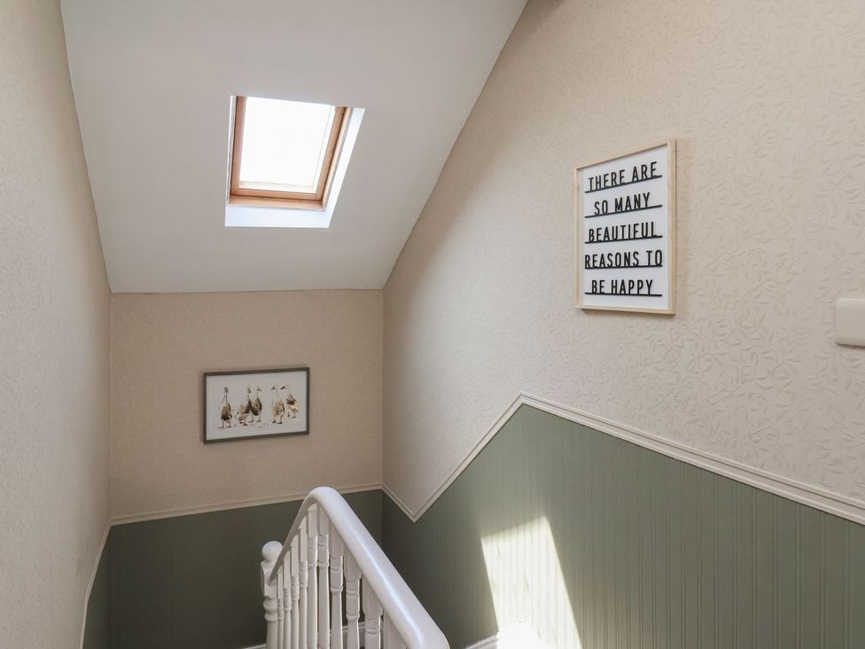 A hallway with a staircase and wall art at Crescent Bay House in Filey