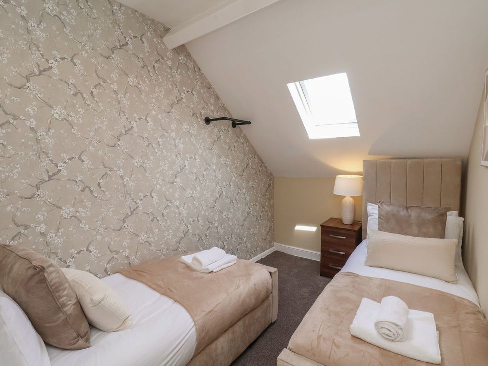 A bedroom with two beds and a nightstand at Crescent Bay House in Filey