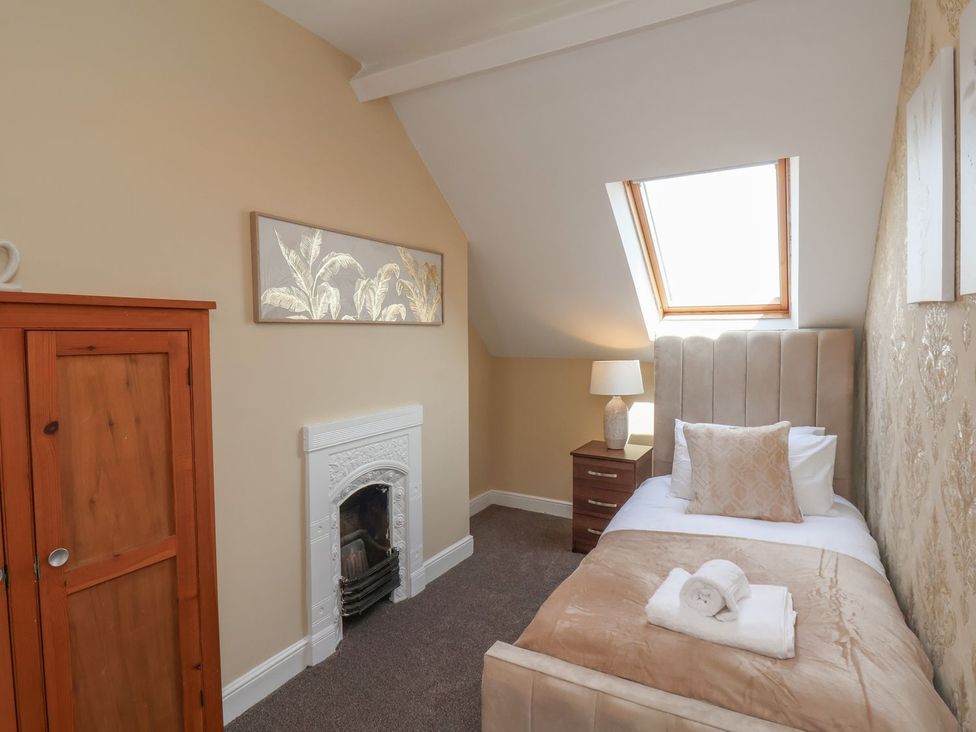 A bedroom with a single bed and furniture at Crescent Bay House in Filey