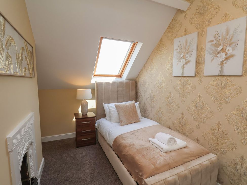 A bedroom with a single bed and wall art at Crescent Bay House in Filey