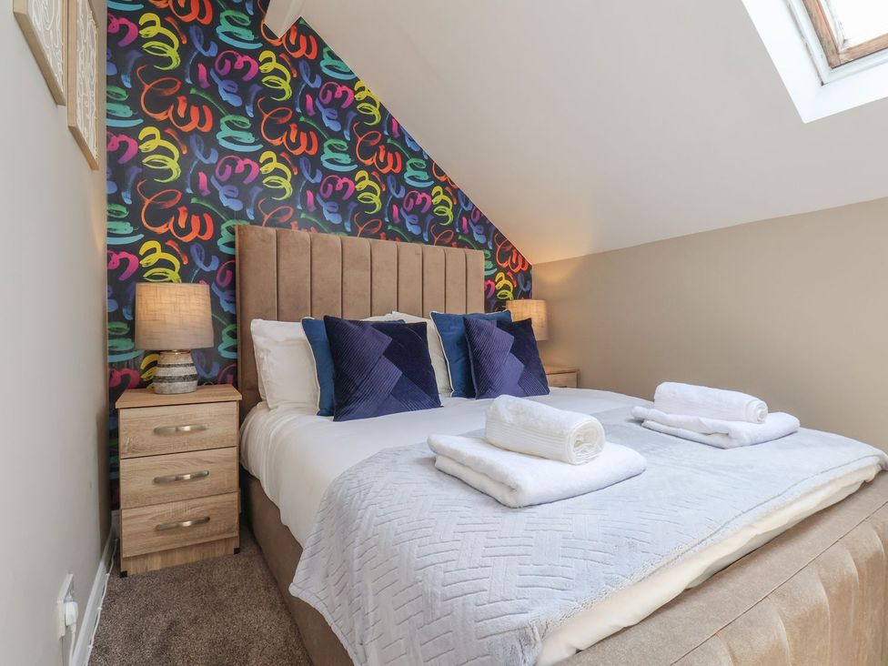A bedroom with a bed and colorful wall decor at Crescent Bay House in Filey