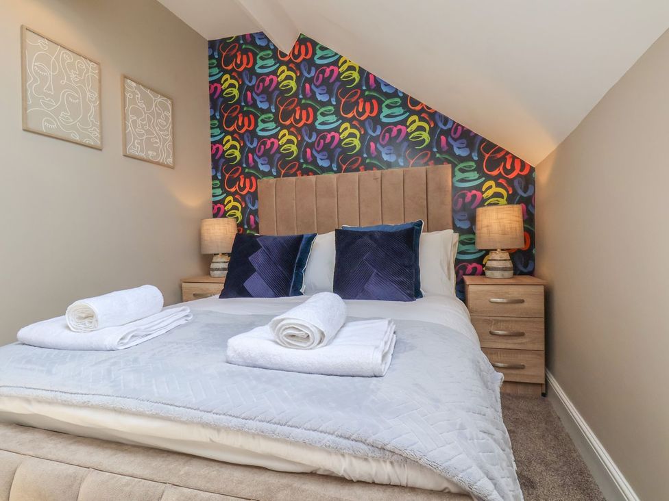 A bedroom with a bed and colorful wall art at Crescent Bay House in Filey