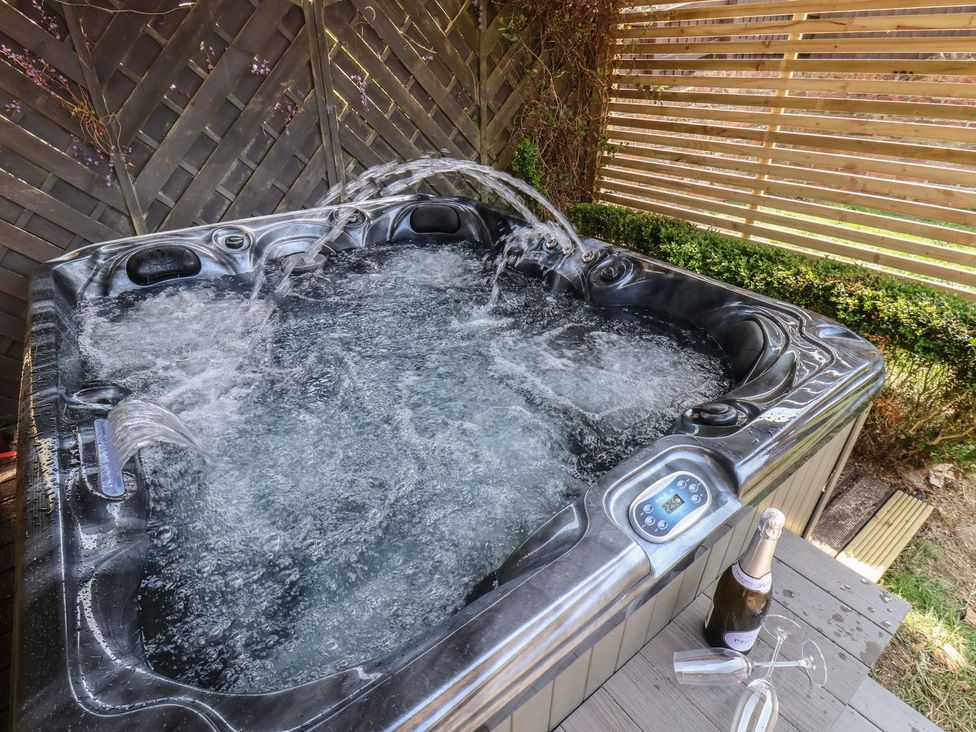 A hot tub with water and champagne on a wooden deck at Crescent Bay House in Filey