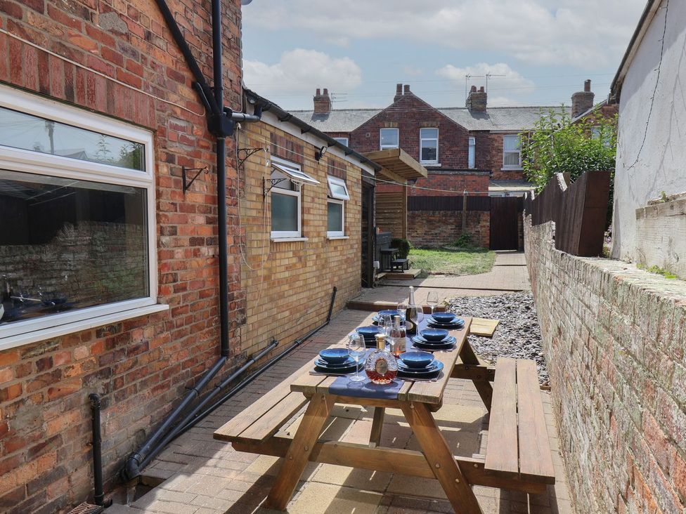 A garden with a wooden table and chairs set at Crescent Bay House in Filey