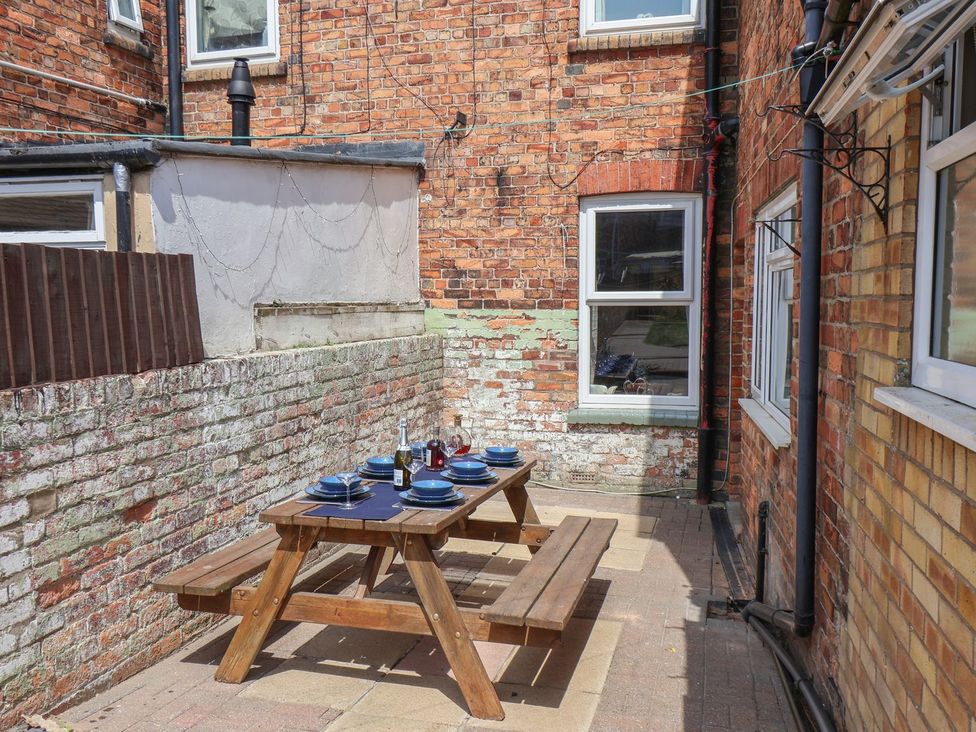 An outdoor dining area with a wooden table and chairs at Crescent Bay House in Filey