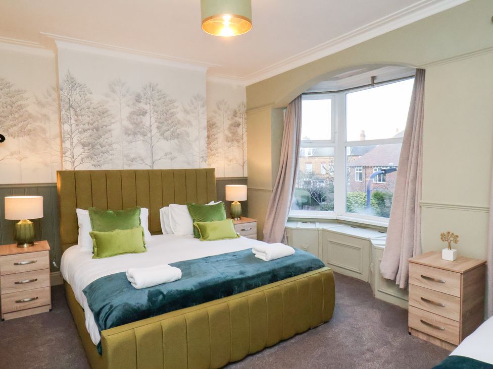 A bedroom with a bed and bedside tables at Crescent Bay House in Filey
