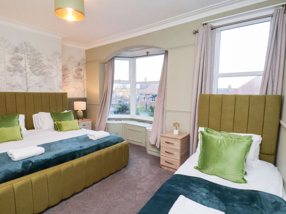 A bedroom with two beds and a window at Crescent Bay House in Filey