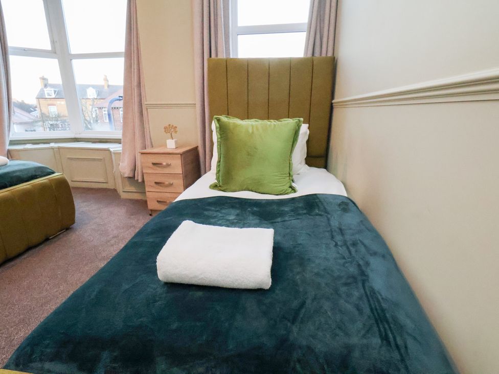 A bedroom with a single bed and bedside table at Crescent Bay House in Filey