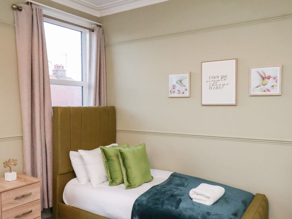 A bedroom with a bed and wall art at Crescent Bay House in Filey
