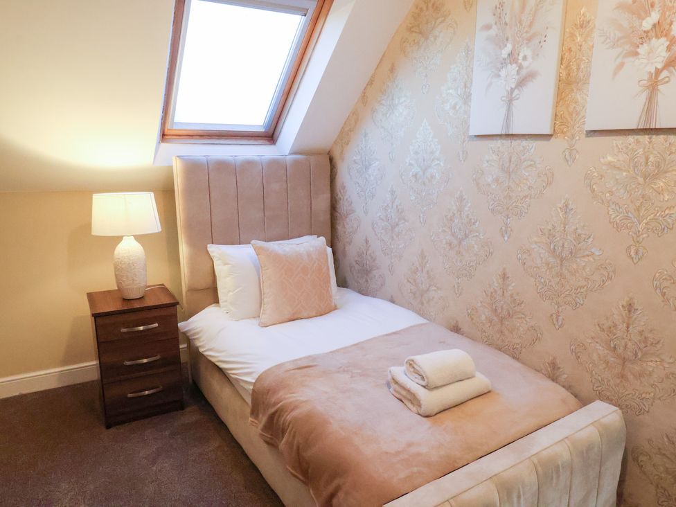 A bedroom with a single bed and lamp at Crescent Bay House in Filey