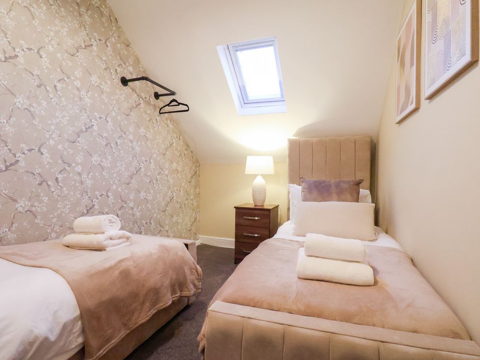 A bedroom with two beds and a side table at Crescent Bay House in Filey