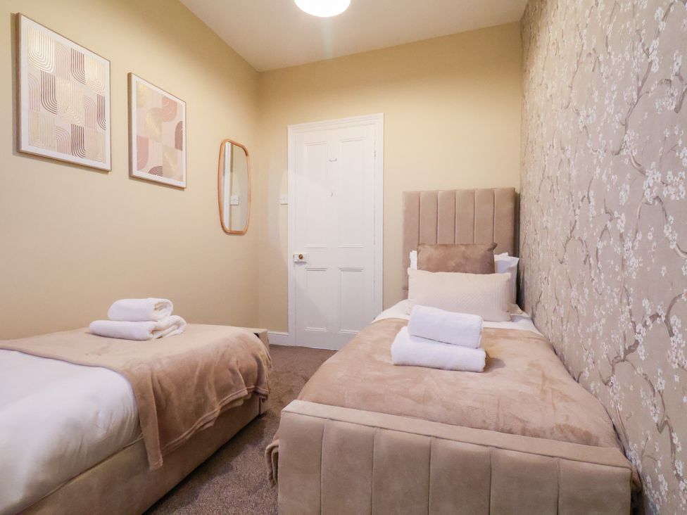 A bedroom with twin beds and wall art at Crescent Bay House Filey