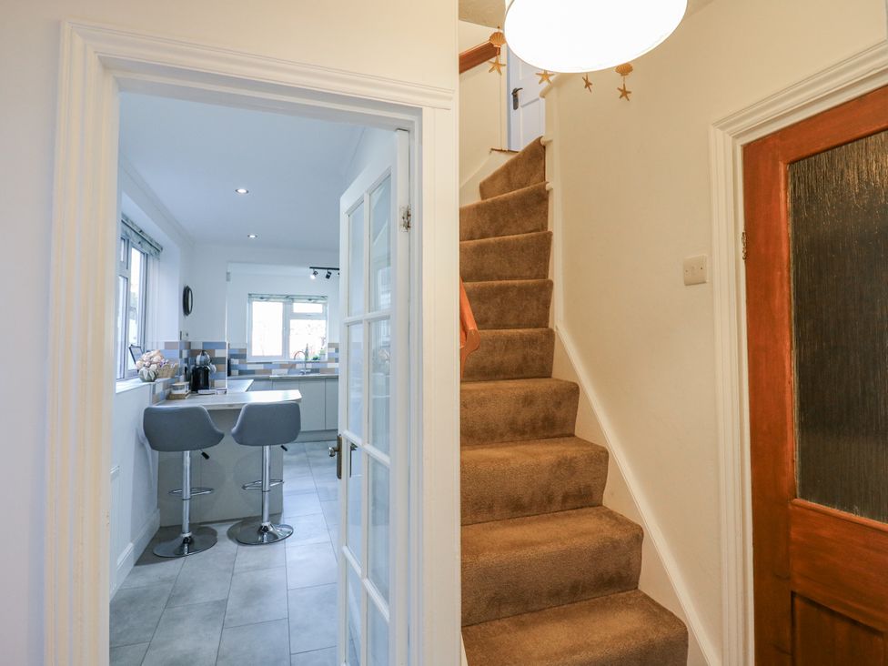 A hallway leading to a kitchen and stairs at Beachside Terrace in Harwich